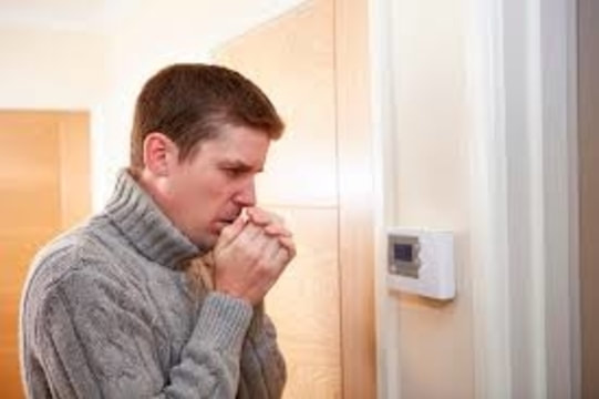 cold man looking at thermostat