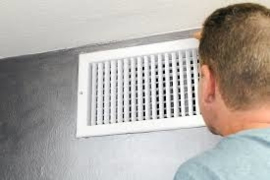 man looking at heat vent
